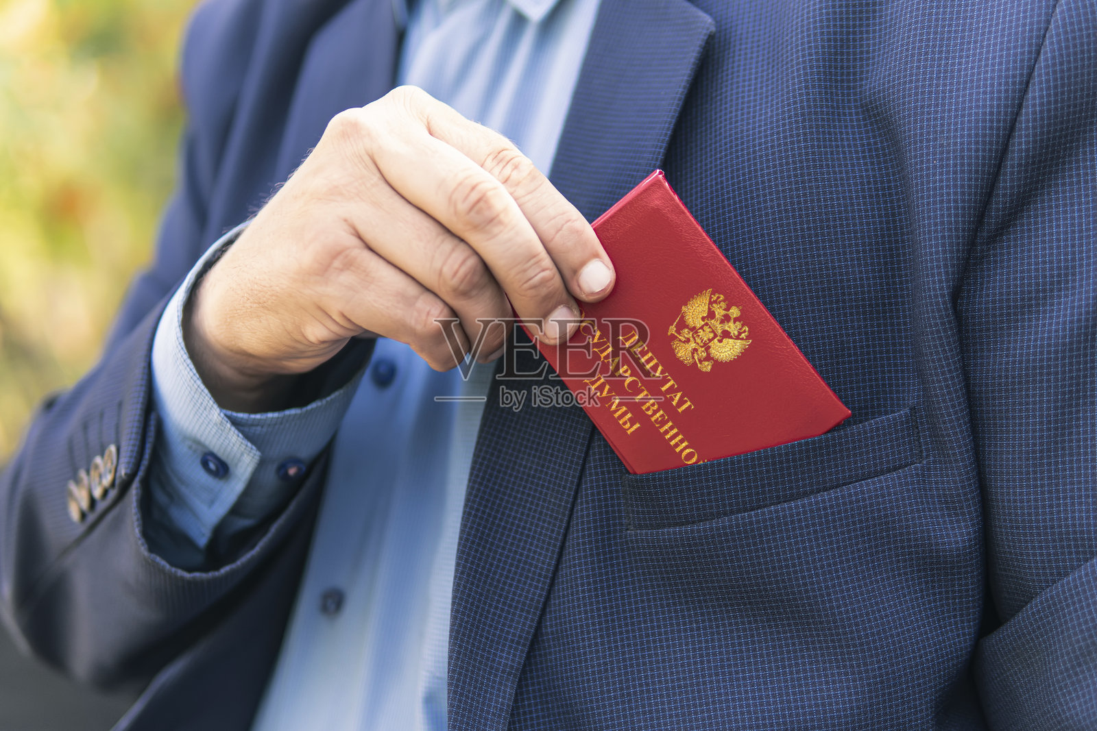 蓝色西装男出示红色身份证或通行证。一个重要的不可接触的部门雇员正在开车。俄罗斯国家杜马代表的题词出现在红色文件上。议会豁免权的概念。照片摄影图片
