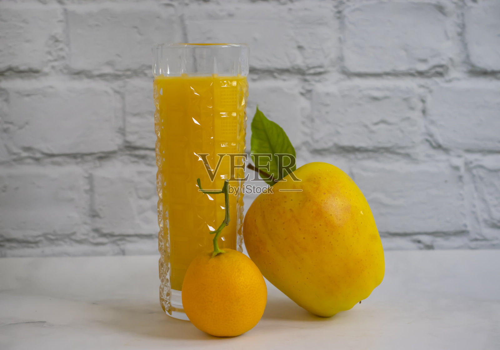 在明亮的背景下，一杯橙苹果汁照片摄影图片