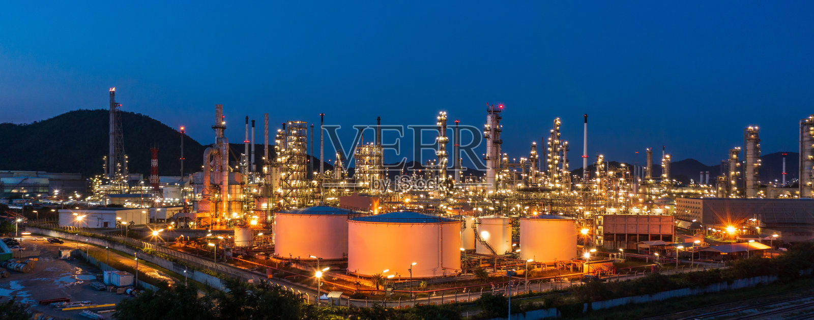 鸟瞰图。炼油厂和储油罐在黄昏和夜间。石化工业。横幅全景照片摄影图片