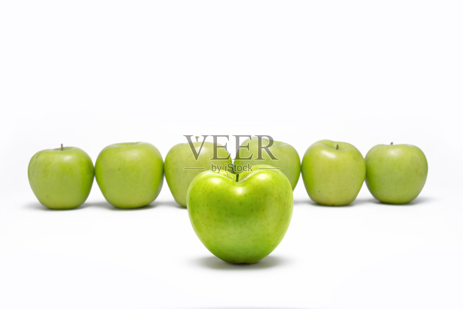 心形的青苹果在其他青苹果前面排成一列。照片摄影图片