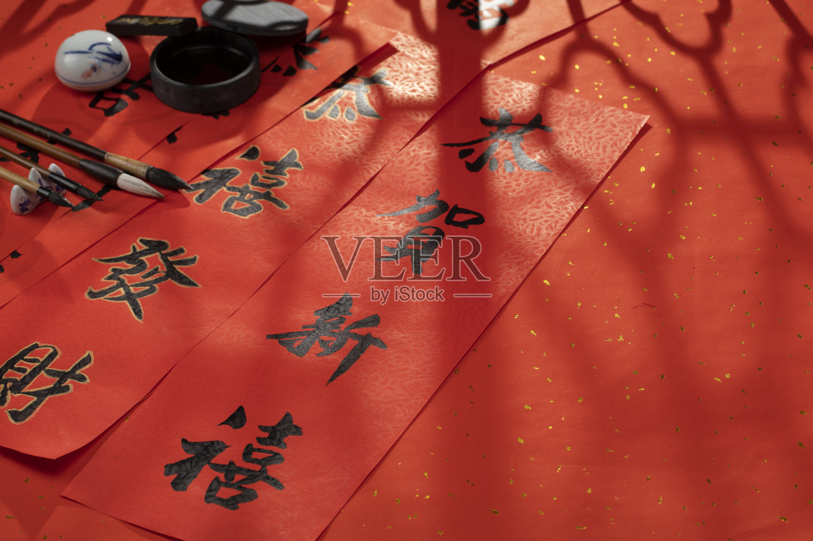 阳光透过窗花照射在中国春节春联和毛笔砚台照片摄影图片