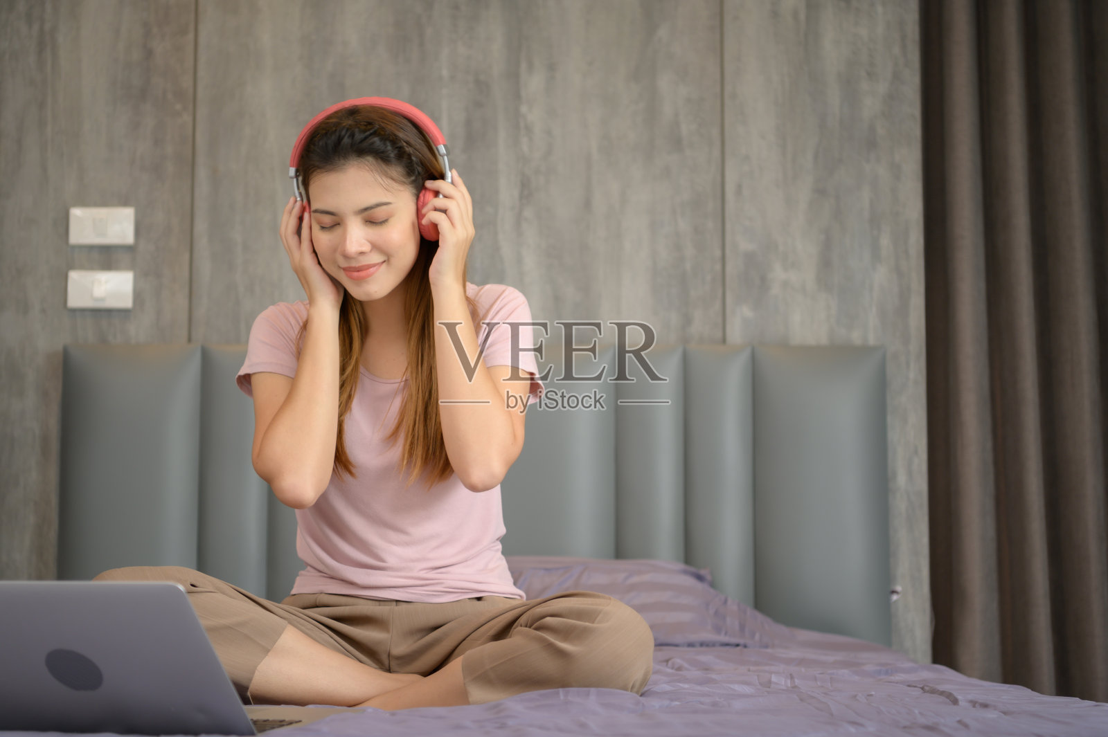 亚洲女性戴着耳机，喜欢听音乐照片摄影图片