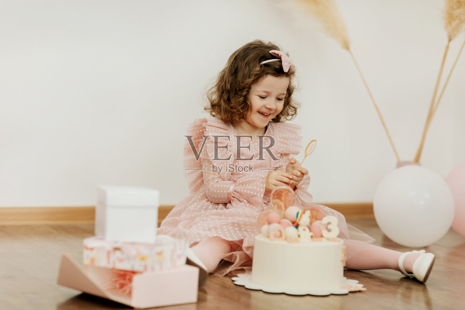 一个可爱的小女孩在她的生日那天拿着蛋糕和礼物坐在地板上开心地笑照片摄影图片
